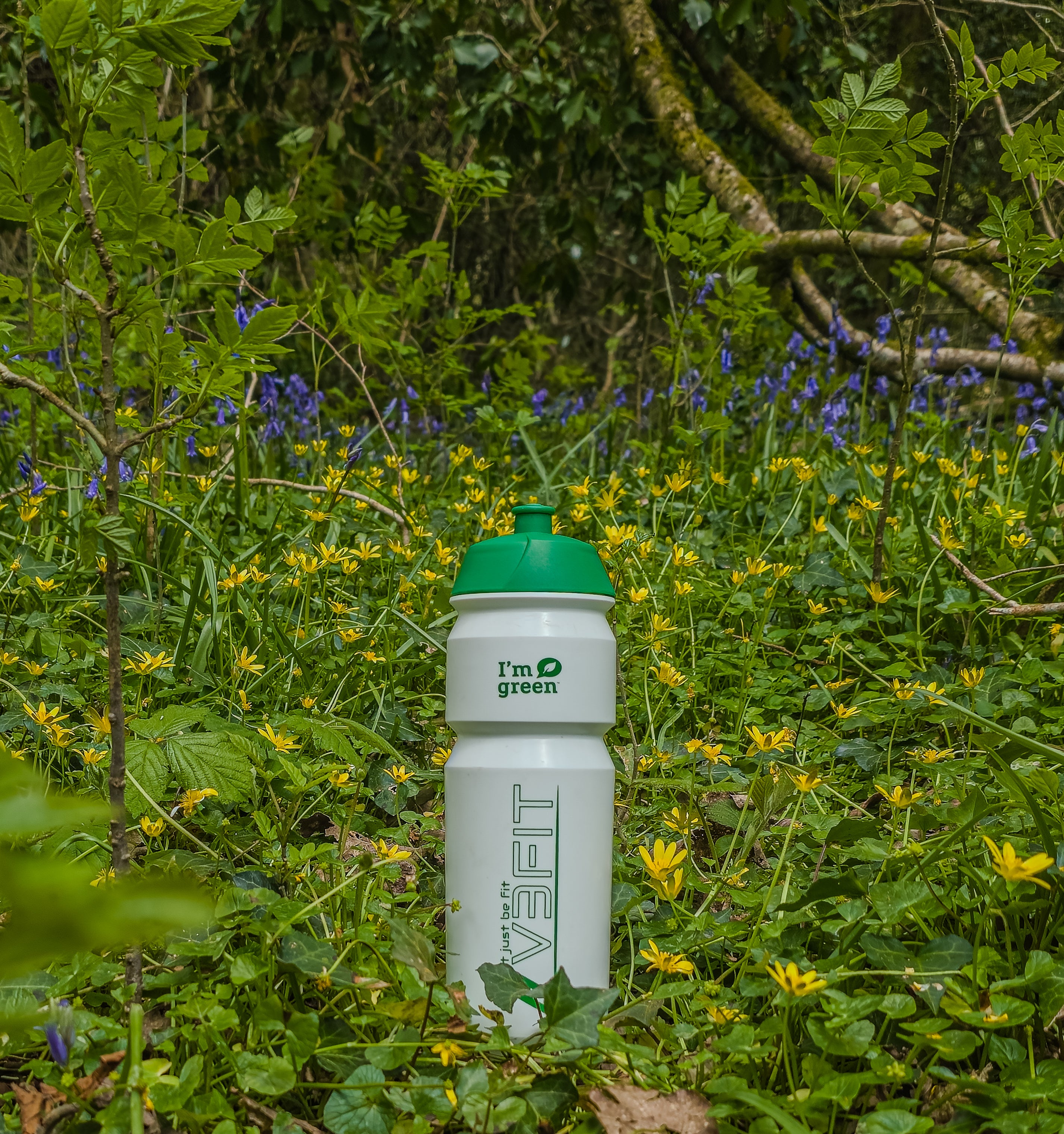 A picture of the v3fit BIOPLASTIC WATER BOTTLE 750ml in a green field surrounded by flowers