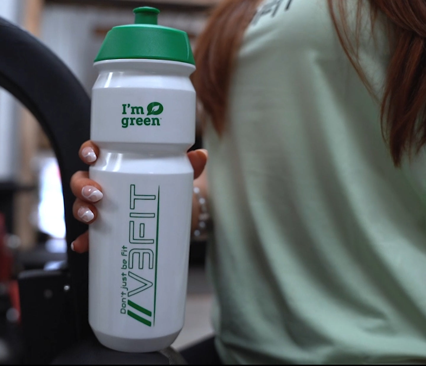 A female holding the v3fit BIOPLASTIC WATER BOTTLE 750ml at the gym